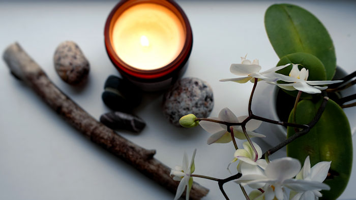 AN orchid, some stones, a piece of driftwood and a lit candle