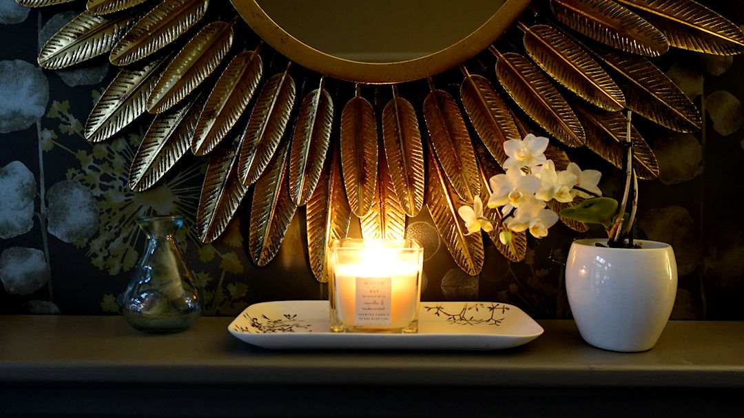 candle on the mantlepiece and a shiny gold mirror